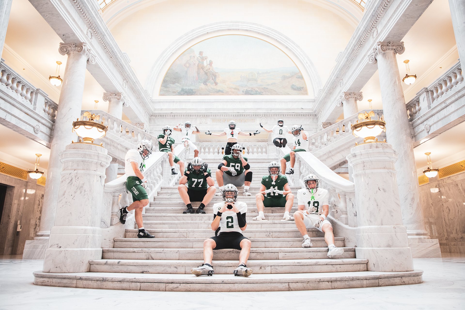 Football team posed on the marble stairs of the Utah State Capitol