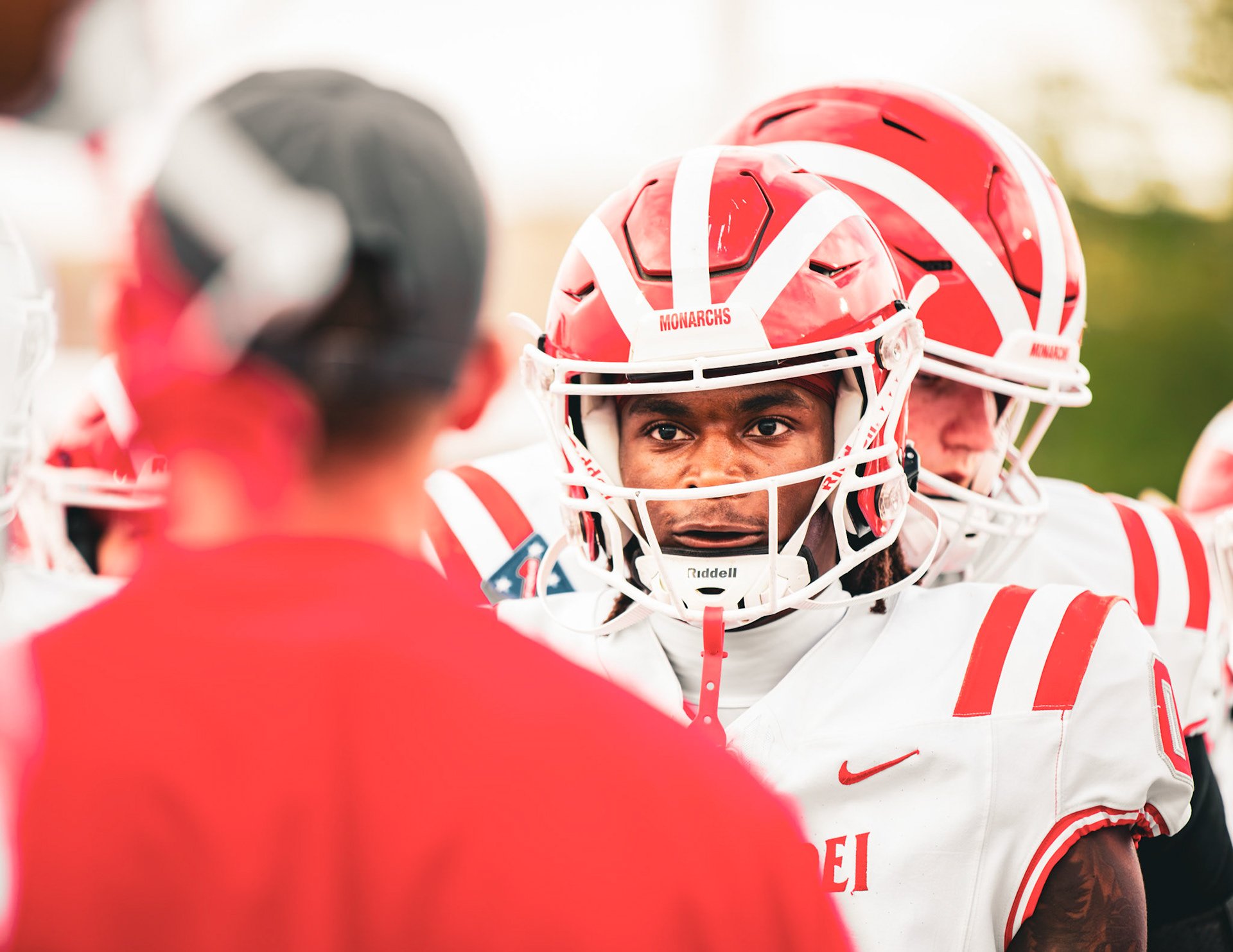 Close-up portrait through a red football helmet facemask