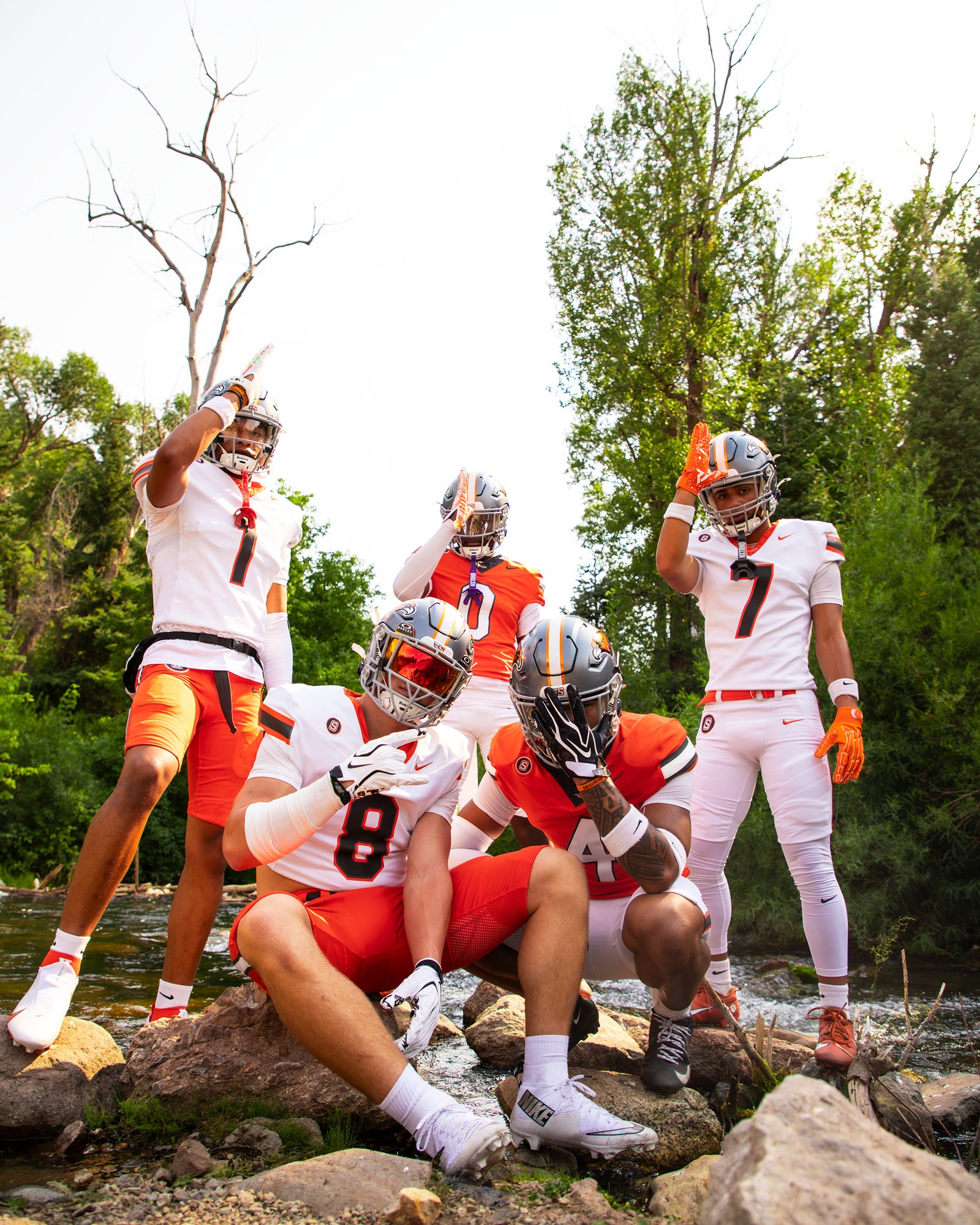 Players posed together on rocks along a mountain creek
