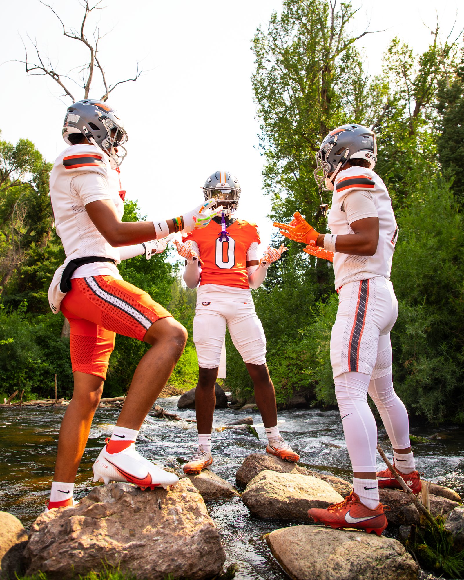 Three players talking on rocks along a mountain creek